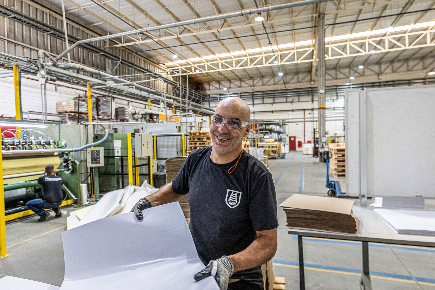 Un uomo in una fabbrica tiene in mano un pezzo di carta.