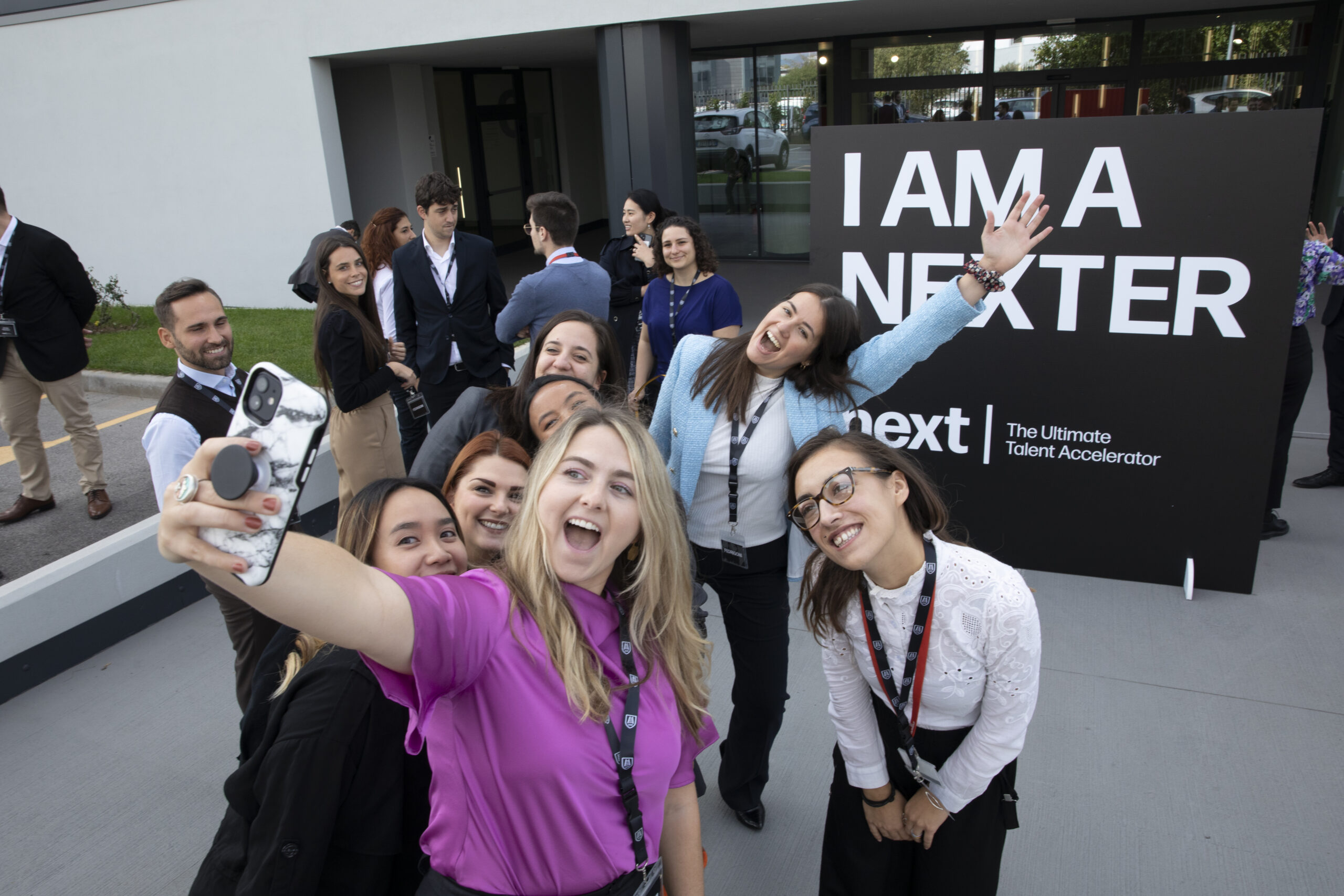 Un gruppo di persone che si scattano un selfie davanti a un cartello che dice I am a Nexter